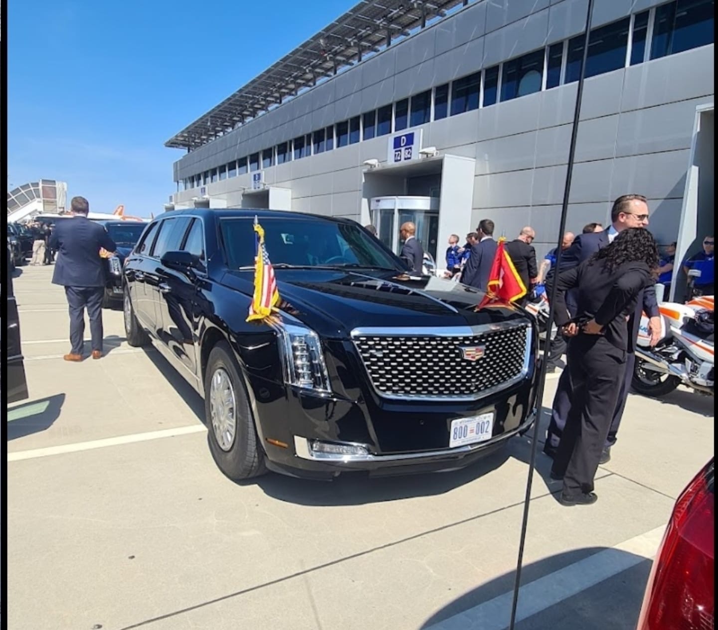 Chauffeur ouvrant la porte d'une berline noire à l'aéroport de Genève la nuit